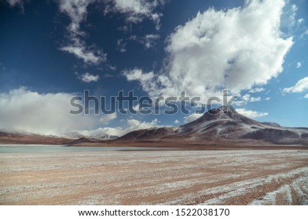 Dramatic snowcapped mountain landscape wilderness. Dry, barren landscape with beautiful mountain background. Mountain range view. Salt Flats of Uyuni, Bolivia. Copy space, blue sky and sand dust