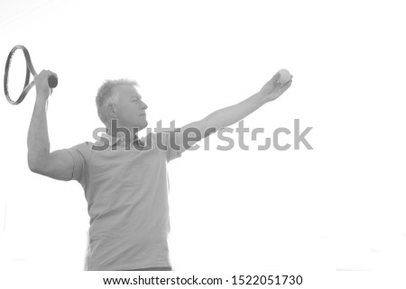 Black and white photo of senior athlete hitting ball with tennis racket