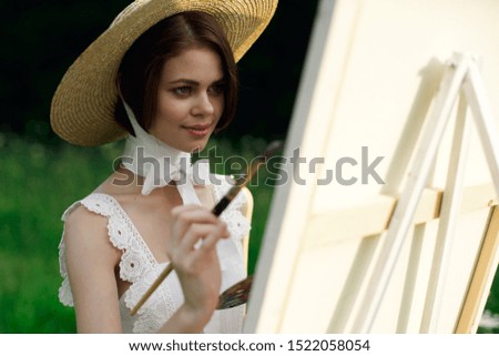 woman looks at a white canvas with a brush for painting