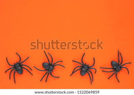 The toy spider on orange background. Halloween decoration. Festive card, celebration frame, banner. Top view. Holiday symbol. Copy space.