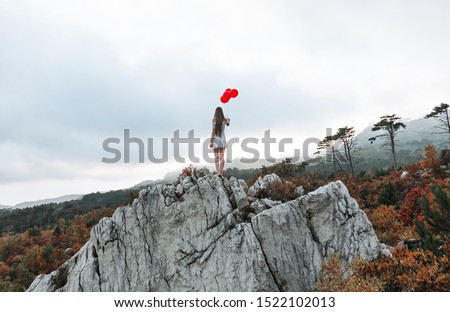 a lonely girl in a white dress and a red balloon walks through the autumn forest, depressing atmosphere