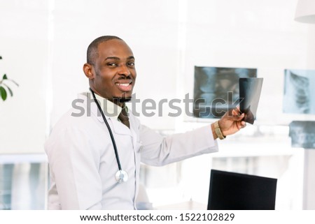 Portrait of a doctor looking at a radiography. African-American black smiling doctor man in the hospital