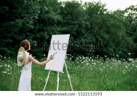 beautiful woman paints a picture of a beautiful landscape
