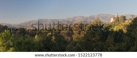 Panoramic view of the Arroyo Seco, the Colorado Street Bridge, and the Richard H. Chambers Courthouse against the San Gabriel Mountains in Pasadena.  Royalty-Free Stock Photo #1522123778
