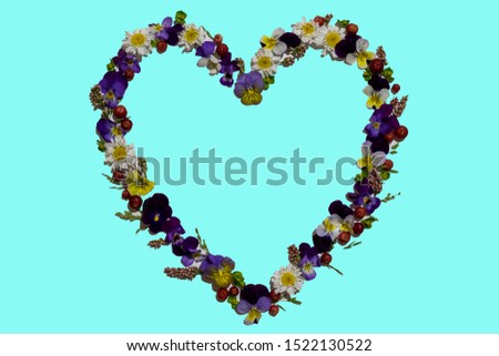 spring and summer heart-shaped Wreath of pansies and daisies, with cranberries and other wildflowers isolated on a blue background