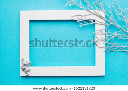 White frame, silver branch and an angel on a blue background. New year, holiday, decoration. With place for text. View from above