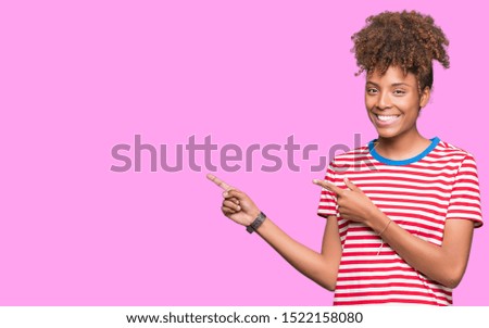 Beautiful young african american woman over isolated background smiling and looking at the camera pointing with two hands and fingers to the side.