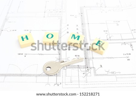 Silver key and word home lying on construction drawing of house