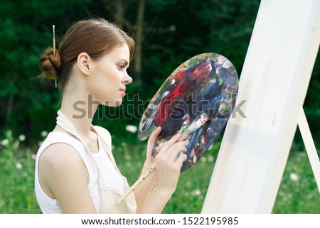 woman young girl easel paints a picture with paints