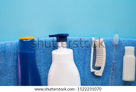 White shampoo bottle, baby soap, comb, towel, blue suscreen bottle. Natural organic bath products. Bathroom items. Flat lay stock photo for web site and beauty blog.