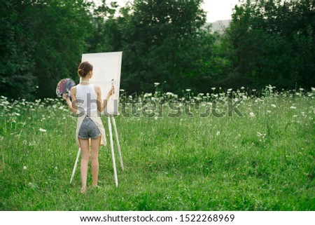 woman young girl easel paints on a canvas on nature