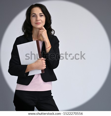 Close-up portrait of an adult pretty brunette woman in a business suit with magnificent black hair on a white background in studio. Beauty, model posing.