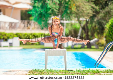 Little happy girl having fun in outdoor swimming pool