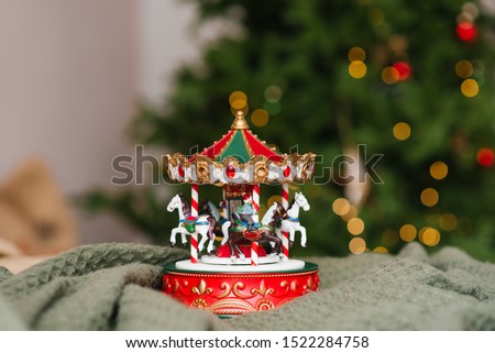 Children's toy carousel on the background of a Christmas tree with burning lights