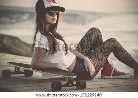 Beautiful and fashion young woman posing with a skateboard Royalty-Free Stock Photo #152229140