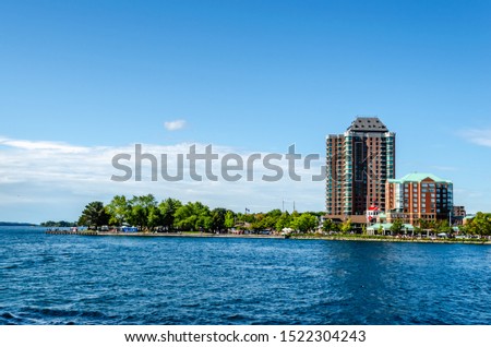 View of a group of waterfront condo buildings on the St. Lawrence River under a blue summer sky.