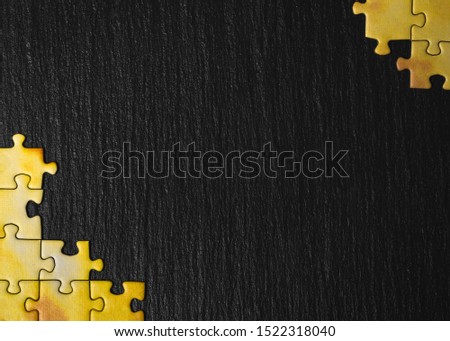 Yellow puzzle on a black stone background. Frame from puzzle around negative space. Royalty-Free Stock Photo #1522318040