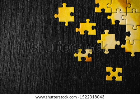 Yellow puzzle on a black stone background. Frame from puzzle around negative space. Royalty-Free Stock Photo #1522318043