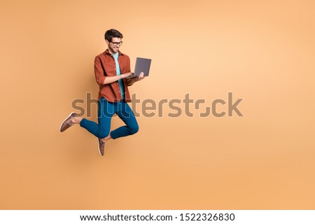 Full length body size view of his he nice attractive cheerful cheery successful brunet guy jumping in air using laptop home-based job isolated over beige color pastel background Royalty-Free Stock Photo #1522326830