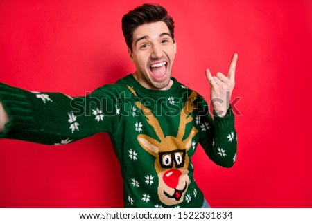 Portrait of funky funny crazy man in deer reindeer sweater make selfie show horned sign scream true rock-and roll heavy metal hipster on christmas event isolated over red color background