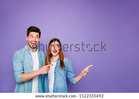 Portrait of romantic excited couple of business people freelancer scream wow look at copyspace point index finger ads tips wear denim jeans clothes isolated over violet purple color background