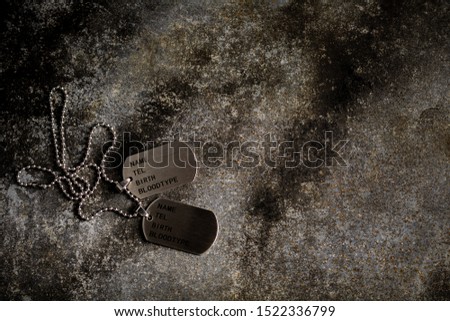 Blank military dog tags on abandoned rusty metal plate. - Memories and sacrifices concept.