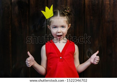 A kid with props for a photo booth gives a thumbs-up. The child with the requisite mustache on wooden background. Little boy approves.