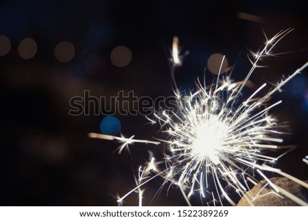 Bengal fire sparkles against the background of city lights, blurred bokeh.  A lot of sparks 
