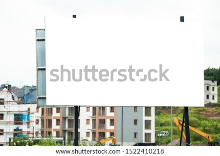 Blank white advertising billboard in the front of construction site on residential area