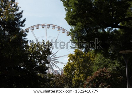 Beautiful ferris wheel with white cabs on a background of blue sky