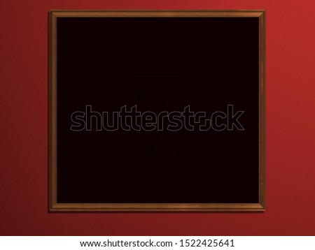 Black picture in a wooden frame against the background of a red wall.