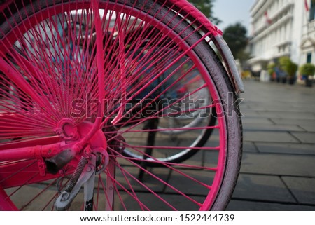 Cropped image of retro styled wheels of pink colored nineteenth century bicycle with bokeh, shallow depth of field focus.