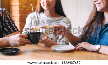 Closeup image of people clinking and drinking coffee together in cafe