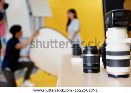 Behind the scenes, photographers are using reflex to shooting pictures of beautiful young women models smiling and posing in the studio with the backdrop and studio lights. Selective focus