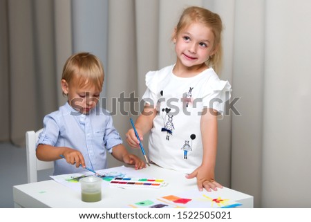 Brother and sister, girl and boy paint with watercolors at the t
