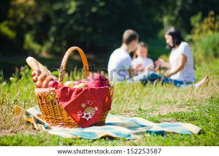 Picnic Basket with apples and bread. Family disfocused Royalty-Free Stock Photo #152253587