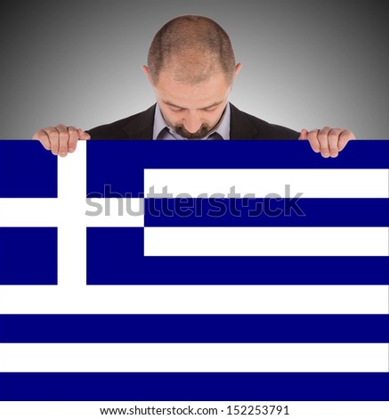 Smiling businessman holding a big card, flag of Greece, isolated on white