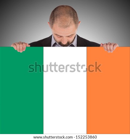 Smiling businessman holding a big card, flag of Ireland, isolated on white