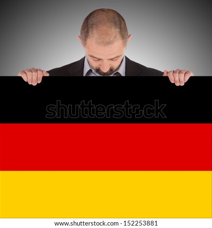 Smiling businessman holding a big card, flag of Germany, isolated on white