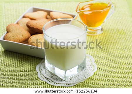 Fresh milk  in glass, sweet cookies, honey  on wooden background. Selective focus.