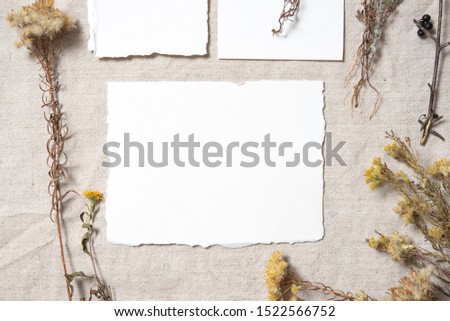 Blank greeting cards with dry flowers on rustic textile background for creative work design. Vintage wedding invitations. Overhead view. Flat lay, top view invitation card with copy space. Mockup 