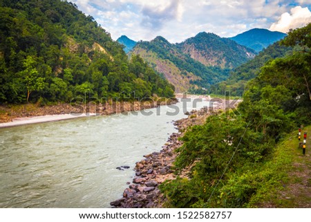 Landscape of mountains in Rishikesh along side river Ganga flowing in the monsoon season in Uttarakhand, India. Rishikesh, Yoga city India, Ganga River valley, Sunrise Uttarakhand. River rafting 