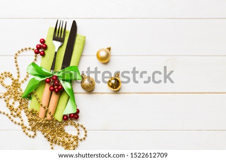 Top view of holiday set of fork and knife on wooden background. Christmas decorations and toys with copy space. New Year Eve concept.