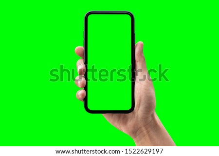 Hand holding smartphone isolated on green background.