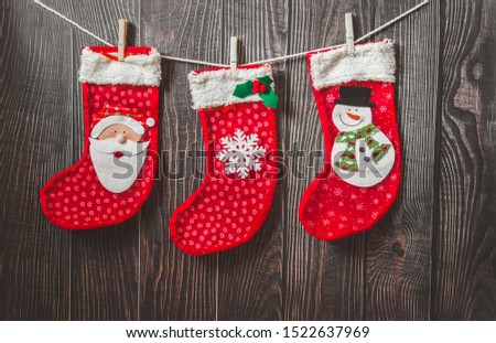 Three red stocking with fir-tree branches and christmas decorations on wooden table