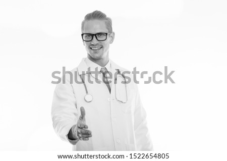 Studio shot of young happy man doctor smiling while giving handshake