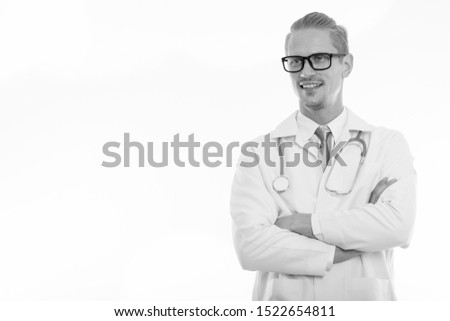 Studio shot of happy handsome man doctor smiling and thinking with arms crossed