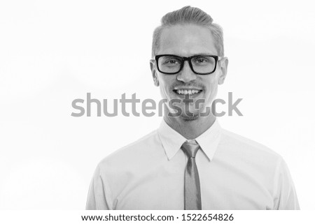 Studio shot of young happy businessman smiling and wearing eyeglasses