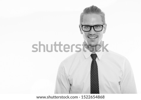 Studio shot of happy young handsome businessman smiling while wearing eyeglasses