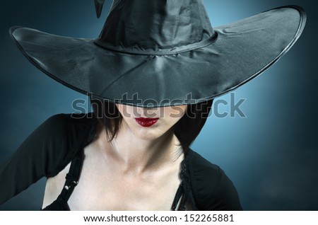 Young woman in a witch costume, her face covered with a hat